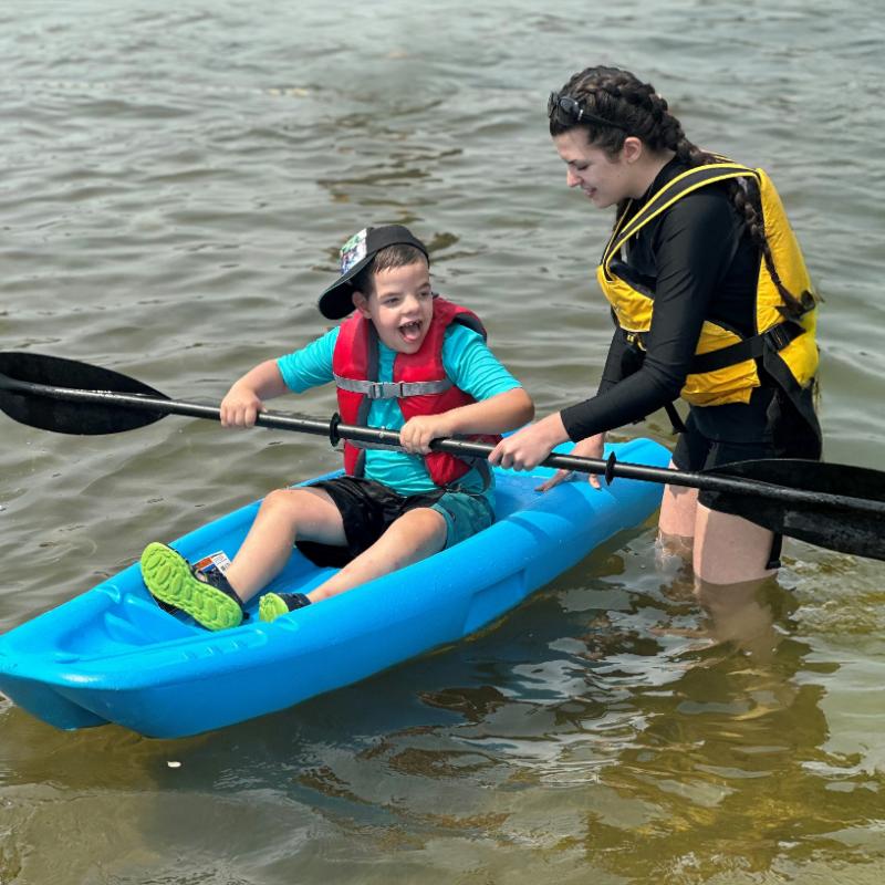 2026 - One Kids Place Summer Camp Summer Camp Staff helping young boy with Kayak in the water